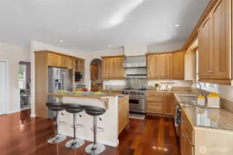 This kitchen is all about elevated living! Beautiful hickory cabinets complement the chic granite countertops, while the bar-height breakfast bar on the center island provides the ideal spot for casual dining or enjoying a glass of wine with friends. An arched doorway frames the view of the formal dining room, effortlessly blending casual and formal spaces.