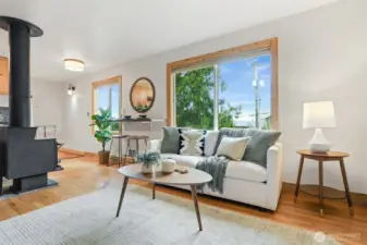 Main home living room with hardwood floors, woodstove, western views of the ship canal, and custom built in entertainment center.