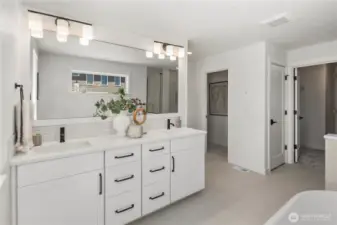 Primary Bathroom – Vanity: The spa-inspired primary bathroom features a double-sink vanity with sleek finishes, modern fixtures, and ample storage for everyday convenience. A wide mirror and abundant lighting elevate both style and functionality.  Staged photos are of the model home of the same floorplan within the Foxmoore community and are for visualization purposes only. Colors, finishes, and layout can and will vary.