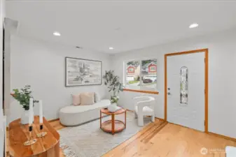 Living area with laminate flooring, recessed lighting, and a staircase leading to the upper level. Neutral finishes provide a bright and versatile space.