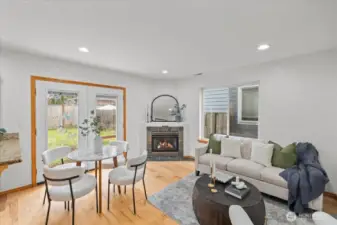 Open dining area with space for a table near glass doors leading to the backyard. Adjacent living area features a fireplace and large window for natural light.