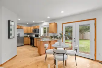 Dining area positioned next to glass doors providing direct access to the backyard. Open-concept design connects the dining space with the kitchen and living area.