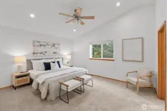 Spacious primary bedroom with high ceiling, ceiling fan, and large window for natural light. Carpeted flooring and neutral finishes create a comfortable retreat.