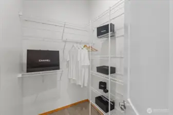 Walk-in closet with built-in wire shelving and hanging space for organized storage. Carpeted flooring and multiple shelves provide room for clothing and accessories.