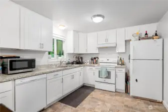 Large updated kitchen with white shaker cabinets, quartz counter tops and undermount sink.