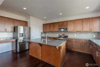 Central granite island with sink and eating bar. Walk-in pantry keeps essentials organized and accessible. Planning desk provides dedicated workspace.