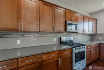 Full-height backsplash adds style and durability. Soft-close cabinets provide functional storage. Stainless steel appliances designed for modern living.