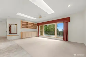 Large living room with built-in cabinets, surround sound speakers, skylights and a slider out to your very spacious deck.