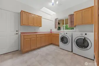 Large utility room with tile floors and ample cabinet space. Washer & dryer stay.