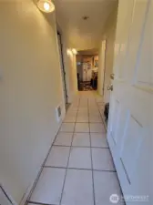 The kitchen with eating area & living room are at the end of the entry hallway. The laundry nook is behind the open door. One the left is the primary bedroom (being used as a home office) along with the primary bath. On the right side of the hallway is the second full bathroom.
