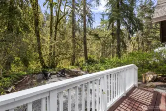 The back deck features a charming railing and overlooks the creek and cozy firepit.