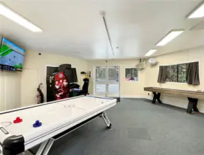 Rec room with air hockey, video games and shuffle board.