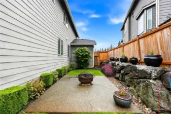 East side of the home has aggregate patio for easy maintenance plus flower pots that stay and garden space along the fence.