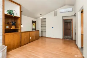 The other side of the living room has a TV mount with a lighted display area above and wood storage below behind the hidden door. Wood stove is on the left. Another ductless mini, a small desk area and shelving. THis was set up with recliners for TV viewing.