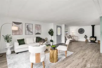 Spacious living room flows seamlessly into the adjacent den featuring a cozy wood-burning stove—perfect for relaxing or creating a flexible bonus space.