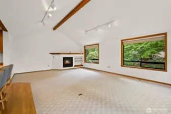 Vaulted great room with large windows and gas fireplace.