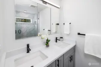 Primary bathroom with dual sinks, heated floors and tiled shower with glass door.