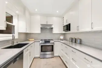 The remodeled epicurean kitchen features custom cabinetry, quartz countertops, stainless appliances, a cozy breakfast nook, and window seat.