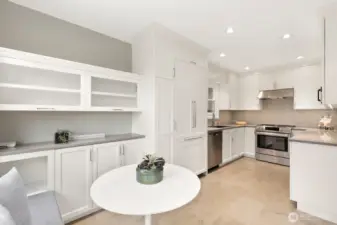 The remodeled epicurean kitchen features custom cabinetry, quartz countertops, stainless appliances, a cozy breakfast nook, and window seat.