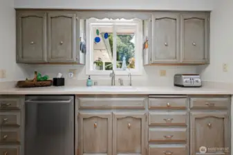 Plenty of storage in these beautifully custom painted cabinets. Window looks out to the back deck
