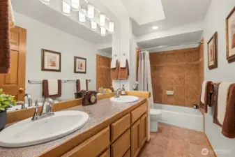 Main upstairs bathroom features beautiful tilework, skylight and new mirror and lighting.