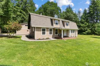 This inviting 2-story home sits peacefully in the center of a lush, open clearing surrounded by towering evergreens. With its classic cabin-style design, covered front porch & charming dormer windows, this home blends rustic appeal with modern updates. The expansive lawn is perfect for entertaining, outdoor dining, or simply relaxing in the quiet of nature. Enjoy morning coffee or evening BBQs in your private Pacific Northwest paradise—just under 10 acres of pure tranquility.