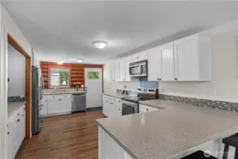 Bright & Updated Kitchen with Modern Touches  Welcome to a beautifully refreshed kitchen that blends functionality and charm. Featuring crisp white cabinetry, durable quartz-look countertops, and a stylish glass mosaic backsplash, this space is made for both everyday living and entertaining.