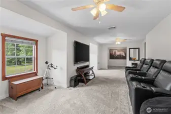 Spacious Bonus Room with Home Theater Setup & Scenic Views  This expansive upstairs bonus room offers endless possibilities—whether you're creating a home theater, game room, or second living space. Featuring plush carpet, dual ceiling fans, & a cozy media wall with reclining theater seating, it’s perfect for relaxing or entertaining. A large window brings in natural light & peaceful views of the surrounding acreage. A rare find in rural homes, this space blends comfort, flexibility & lifestyle in one inviting retreat.