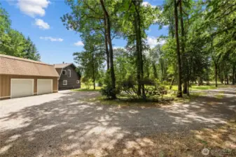 This property features a detached 2-car garage and a charming Pacific Northwest-style log-sided home, all nestled on nearly 10 acres of private forested land. The extended gravel driveway offers ample RV parking, toy storage, and easy access to both the garage and the home’s rear entry. With a 5-bay metal shop also on the property, this is a dream setup for buyers looking for a home with shop space in Washington, or anyone needing room for tools, equipment, or home-based business needs. Ideal for those searching for a rural home with garage and workshop or a multifunctional property with acreage.