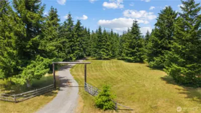 Gated Entry with Rustic Charm – Welcome Home  Begin your journey down the 880-foot-long private driveway through this welcoming gated entry framed by tall evergreens & open meadow. This charming rustic gate signals the start of your peaceful escape, offering the perfect blend of privacy & Pacific Northwest beauty. Surrounded by lush, mature trees & manicured grounds, this entry sets the tone for the serenity, space & natural wonder that await deeper into the property. A true country estate feel just minutes from town amenities.