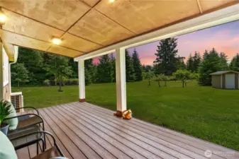 Covered Porch with Sunset Views & Open Acreage  Relax & unwind on this peaceful covered porch, where warm evening skies meet a panoramic view of your private acreage. Overlooking a manicured lawn, orchard trees & a charming outbuilding, this outdoor space is ideal for quiet mornings or golden-hour conversations. Whether sipping coffee at sunrise or enjoying a serene sunset backdrop, this porch captures the heart of country living in the Pacific Northwest—tranquil, timeless & truly one-of-a-kind.