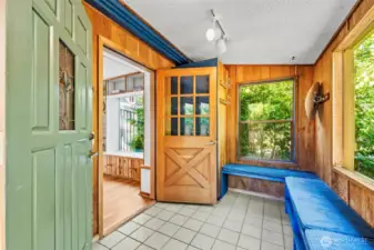 This amazing fully enclosed sun porch is full of windows, built in seating and shoe racks.