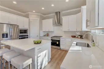 Large kitchen area with oversized island, solid surface, easy to clean quartz counter surfaces, custom white painted cabinetry plus durable hardwood flooring and quality Whirlpool appliances. The perfect area to prepare your meals and snacks and to host get togethers.