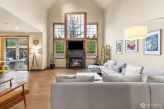 This is the room that makes an impression the second you step in. The vaulted ceiling pulls your eye up, then those five windows stacked across the wall take over, bringing in light all day and giving the fireplace a proper backdrop. The gas fireplace sits comfortably with its tile surround, simple and classic, while the wood wrapped windows and pane detailing add just enough character. Underfoot, the thick maple floors add a rich, grounded feel that balances all that openness. The palette stays warm and neutral, so it feels inviting right away, and with the slider nearby off the breakfast nook, it’s set up perfectly for easy indoor outdoor flow.