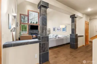 From the front door, this is the view that pulls you straight into the heart of the home. The entry opens toward the family room, framed by slate capped half walls and those matching slate wrapped pillars that give the whole space a little architectural attitude. It’s a nice balance, you get separation from the entry without closing anything off. Those ledges are just asking for a few plants or a styled moment, so if you’re into decorating, here’s your stage. Off to the side, there’s another hallway closet near the main floor suite, because this floorplan takes storage seriously!