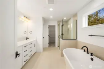 This beautifully designed bathroom features a freestanding soaking tub, dual vanities with abundant storage, and a large glass-enclosed shower. Warm tile tones and modern black fixtures elevate the space into a calming, spa-like experience.    These photos are from Lot 3 at Gooden Hollow, which is the same floorplan. However, Lot 6 will have changes, so all photos, renderings, site maps, and floorplans are for visualization purposes only. Plans, colors, building orientation, finishes, home outlook, and other details can and WILL vary.