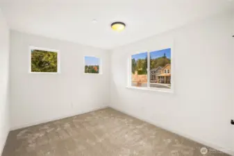 Large windows bring in beautiful natural light and showcase neighborhood and treetop outlooks from this upper-level bedroom. With a spacious footprint and flexible layout, it easily functions as a restful sleeping space or a bright home office.    These photos are from Lot 3 at Gooden Hollow, which is the same floorplan. However, Lot 6 will have changes, so all photos, renderings, site maps, and floorplans are for visualization purposes only. Plans, colors, building orientation, finishes, home outlook, and other details can and WILL vary.