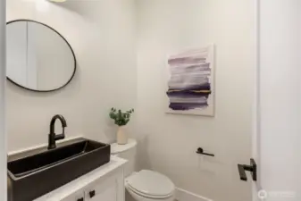 Bathroom with quartz countertop, recessed lighting, white walls, and black fixtures.