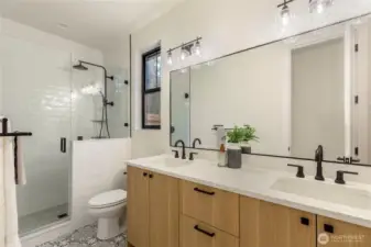 Full bath connected to first floor primary bedroom, glass-enclosed shower with marble accents, and a quartz countertop.