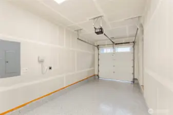 Garage with drywall finish, speckled epoxy flooring, ceiling-mounted opener, and sectional door with windows.
