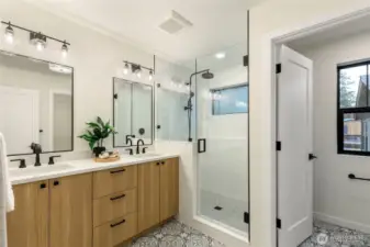 Bathroom with glass-enclosed shower, quartz double vanity, recessed lighting, patterned tile flooring, and a marble trim along the shower entrance.