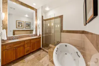 Primary bathroom offers a 5 piece bathroom with the jetted tub.  Toilet has its own room to the left of photo.  Vaulted ceilings throughout this home