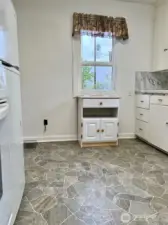 View from the entry to the kitchen showing one of the walls with a mobile stand and one of the two GREAT windows in the kitchen.  I can smell the apple pies cooking.