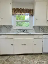 Direct look at the cabinetry, counter & window from the doorway of the of the door to the down stairs garage/shop area