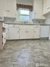 This view of the kitchen from the doorway of the door to the downstairs garage & shop space shows how large the counter space is and how many cabinets there are to make this a kitchen lover's delight