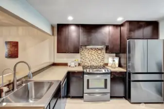 Kitchen with rich dark cabinets, stainless appliances.
