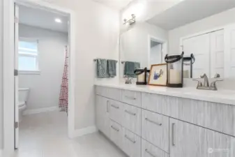 Full bathroom with tub and shower combo. Double sinks and an unbelievable linen closet behind the door as seen in the mirror.