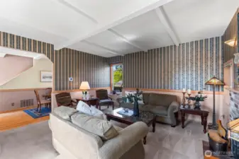 The living room is has a wood- burning fireplace, coffered ceiling, and windows that create a great cross-breeze.