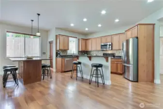 The kitchen is a masterpiece with stainless appliances, a full granite breakfast bar, and exquisite maple/birch cabinets, offering easy-close convenience.