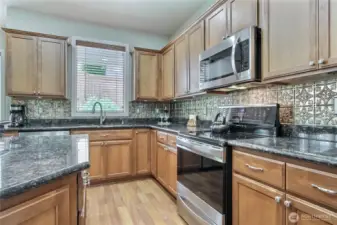 Decorative backsplash, and all stainless appliances: microwave, dishwasher, refrigerator, flat cooktop (ceramic glass), and range.